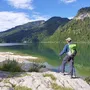 Wanderer mit Rucksack steht am Ufer des Wolfgangsees und blickt auf die Berge.
