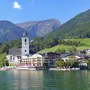 Kirche und Gebäude am Ufer des Wolfgangsees, umgeben von Bergen.