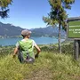Person sitzt am Aussichtspunkt mit Blick auf den Wolfgangsee und Berge.