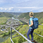 Wanderer mit Rucksack genießt Aussicht auf Mosellandschaft von einem Aussichtspunkt.