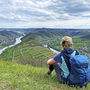 Wanderer mit Rucksack blickt auf Mosellandschaft von einem Hügel.