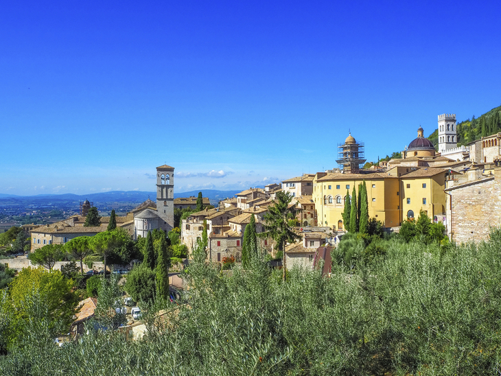 Blick auf die Altstadt von Assisi in Umbrien, umgeben von grüner Landschaft.