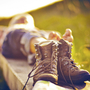 Wanderer entspannt sich im Gras mit Bergstiefeln im Vordergrund.