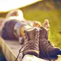 Wanderer entspannt sich im Gras mit Bergstiefeln im Vordergrund.