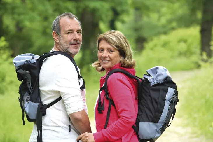 Pärchen beim Wandern im Wald, umgeben von grüner Natur.