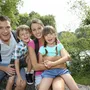 Familie lächelt beim Wandern auf einer Brücke im Grünen.