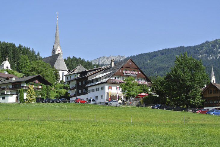 Außenansicht des Kirchenwirts Grosau mit umliegender Landschaft.