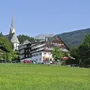 Außenansicht des Kirchenwirts Grosau mit umliegender Landschaft.