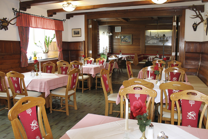 Ein traditionell eingerichtetes Restaurant mit Holzmöbeln und rot dekorierten Stühlen.