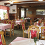 Ein traditionell eingerichtetes Restaurant mit Holzmöbeln und rot dekorierten Stühlen.