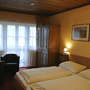 Gemütliches Hotelzimmer mit Doppelbett, Schrank, Sessel und Fenster.
