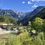 Bergpanorama der julischen Alpen mit Brücke und Fluss im Vordergrund.
