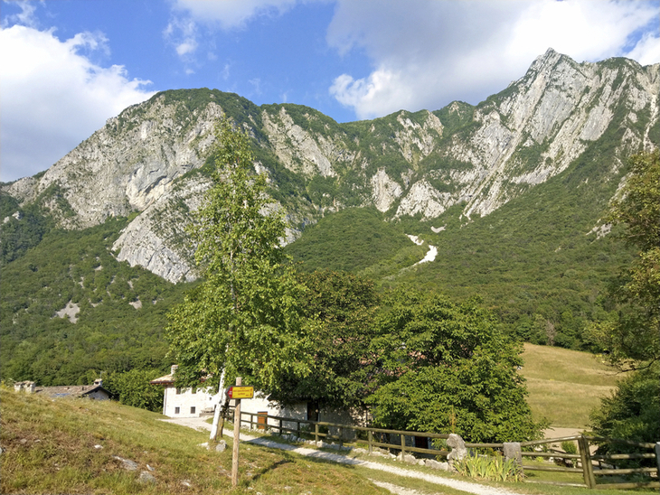 Berglandschaft in Friaul mit Wiesen, Bäumen und einem Wanderweg im Vordergrund