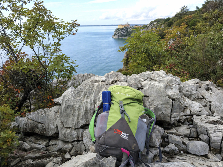 Rucksack auf Felsen mit Blick aufs Meer und Küste in Friaul.