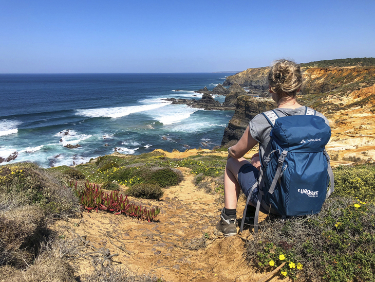 Person am Küstenpfad mit Blick auf das Meer und Klippen in Portugal.