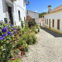 Blumengeschmückte Kopfsteinpflasterstraße in einem malerischen portugiesischen Dorf.