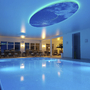 Innenpool im AVALON Bellevue Hotel mit blauer Beleuchtung und Sitzecke im Hintergrund.