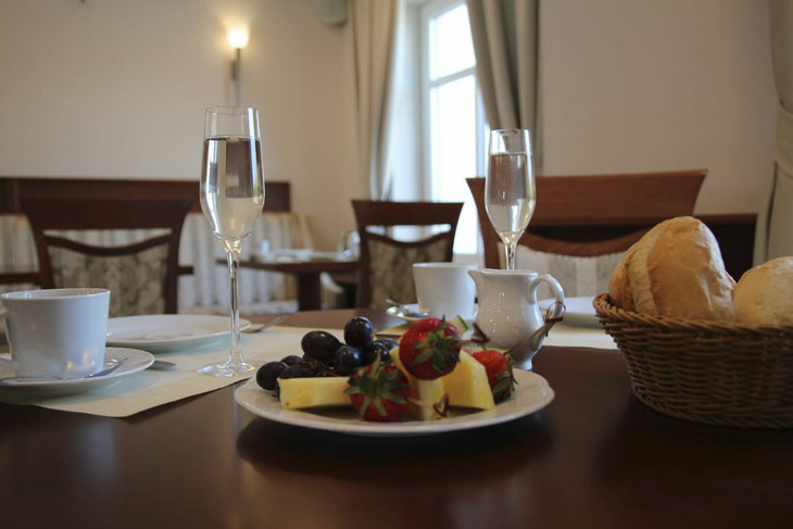 Ein Frühstückstisch mit Brötchen, Obst und Getränken in einem Hotelrestaurant.