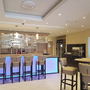 Moderne Hotelbar mit beleuchtetem Tresen und gepolsterten Hockern.