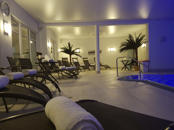 Innenansicht eines Hotel-Schwimmbads mit Liegestühlen und Handtüchern.