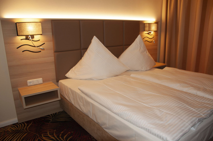 Doppelbett in einem Hotelzimmer mit moderner Beleuchtung.