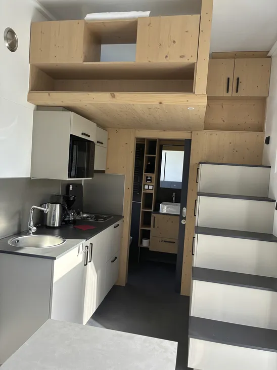 Innenansicht eines modernen Tiny House mit Küchenzeile und Treppe.