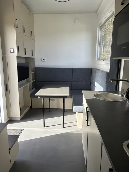 Innenansicht eines modernen Tiny Houses mit Küche und Sitzecke.