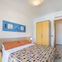 Blick in ein helles Schlafzimmer mit Doppelbett und farbenfroher Bettdecke.