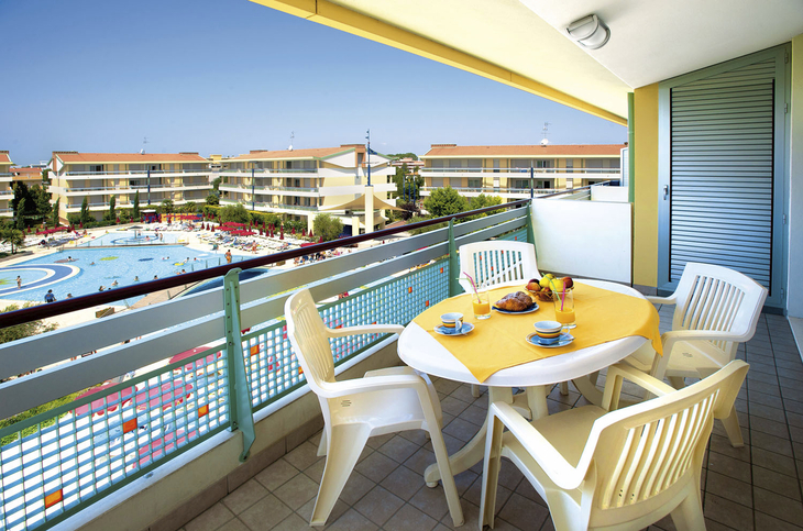 Balkon mit Tisch und Stühlen, Blick auf Pool und Gebäude im Villaggio Planetarium Resort.
