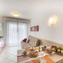 Wohnraum mit Esstisch, Sofa, Fernseher, und großen Fenstervorhängen.