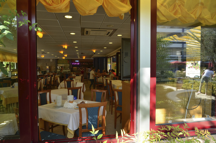 Blick in ein Restaurant mit gedeckten Tischen und gelber Dekoration.
