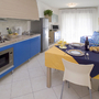 Essbereich mit Tisch, Stühlen, Küche und Sofa in einem Ferienapartment.
