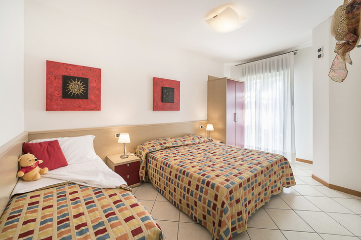 Doppelzimmer mit zwei Betten, farbenfroher Bettwäsche und Dekor an den Wänden.