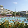 Poolbereich des Villaggio Planetarium Resorts in Bibione mit Gebäuden im Hintergrund.