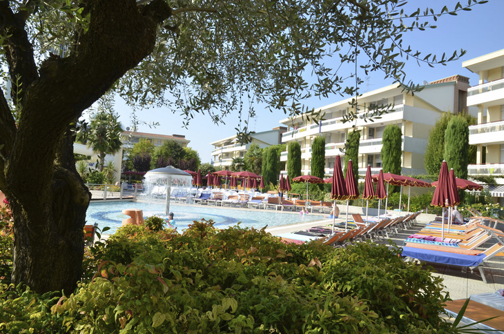 Poolbereich mit Liegestühlen und Sonnenschirmen im Villaggio Planetarium Resort, Bibione.
