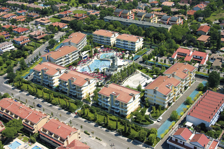 Luftbild des Villaggio Planetarium Resort in Bibione, umgeben von Gebäuden und Grünflächen.