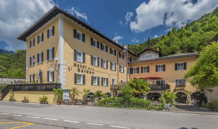 Gelbes Hotelgebäude mit Balkonen und Bergkulisse im Hintergrund.