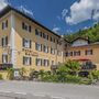 Gelbes Hotelgebäude mit Balkonen und Bergkulisse im Hintergrund.