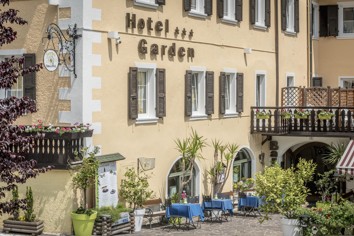 Fassade des Hotel Garden mit Pflanzen und Sitzgelegenheiten im Freien.