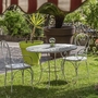Gartenbereich mit einem Tisch und zwei Eisenstühlen auf einer Wiese.