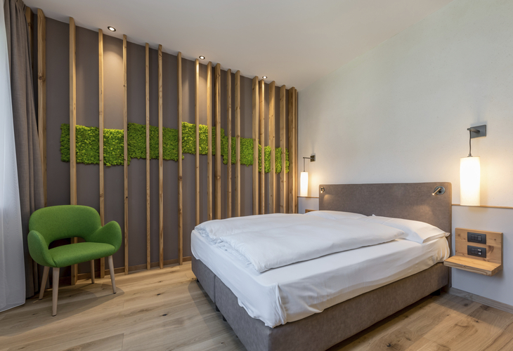 Modern eingerichtetes Schlafzimmer mit grüner Wanddekoration und grüner Stuhl.
