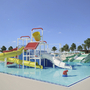 Wasserspielplatz mit Rutschen in einem Ferienpark, Bäume im Hintergrund.