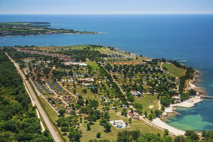 Luftaufnahme eines Ferienparks mit Strand am Meer und umliegender Grünfläche.