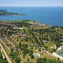 Luftaufnahme eines Ferienparks mit Strand am Meer und umliegender Grünfläche.