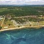 Luftaufnahme eines Campingplatzes am Meer mit grüner Umgebung und klarem Wasser.