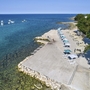 Strandpromenade mit Liegen und Sonnenschirmen am blauen Meer in Umag, Kroatien.