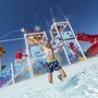 Kind springt in Pool bei Wasserspielplatz mit Rutsche und Sprinklern.
