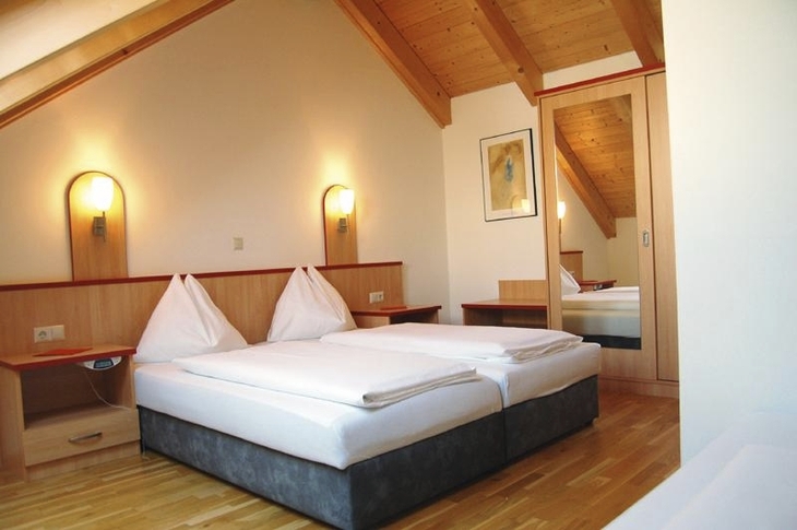 Doppelbett in gemütlichem Ferienparkzimmer mit Holzakzenten und Dachschräge.