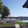 Sonnenliegen am Pool mit Blick auf einen See, Boote und Bäume im Hintergrund.