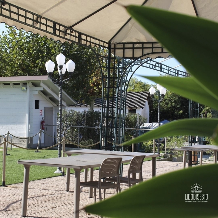 Terrasse mit Tischen und Stühlen unter einem großen Pavillon im Freien